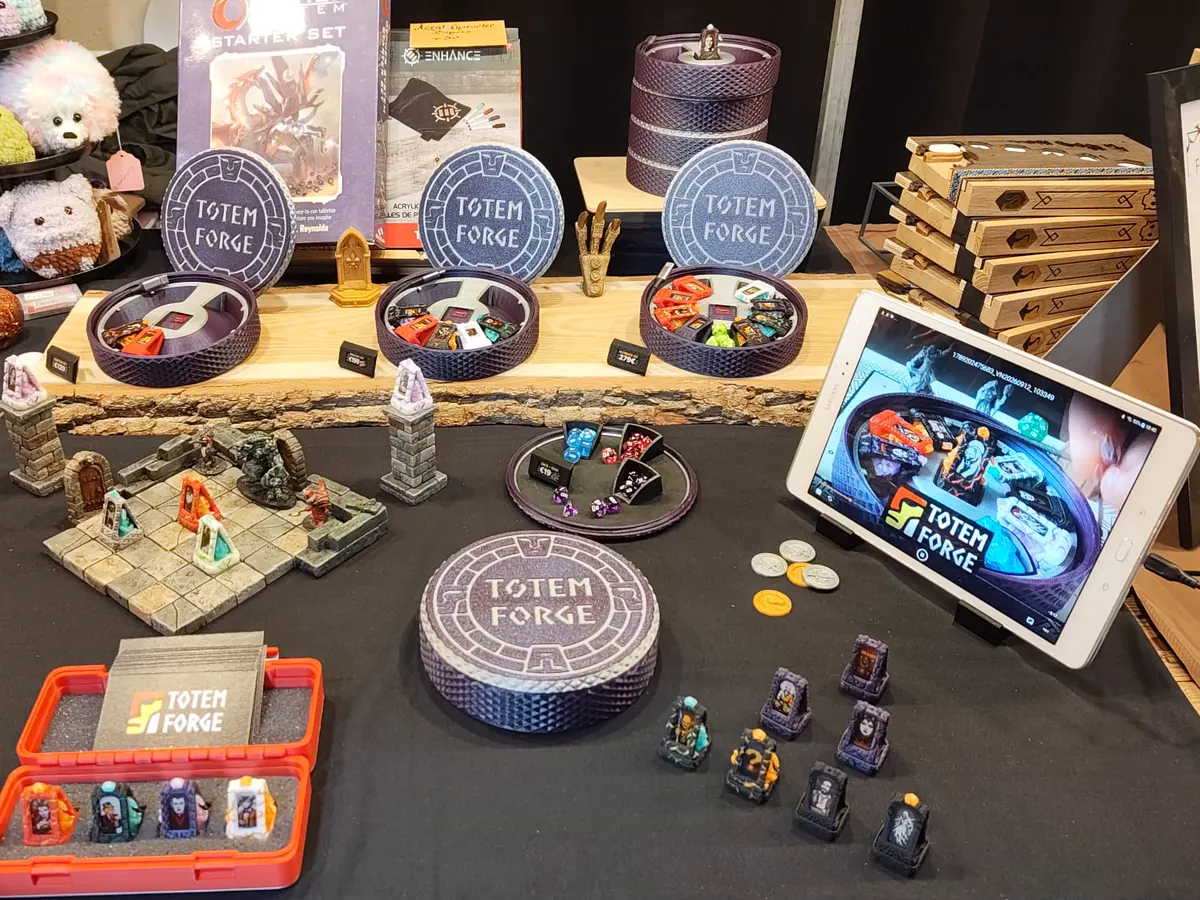 The Totem Forge booth at Main Quest Con 2026: summoning circle cases, loaded totems on a dungeon tile, and the app demo on a tablet