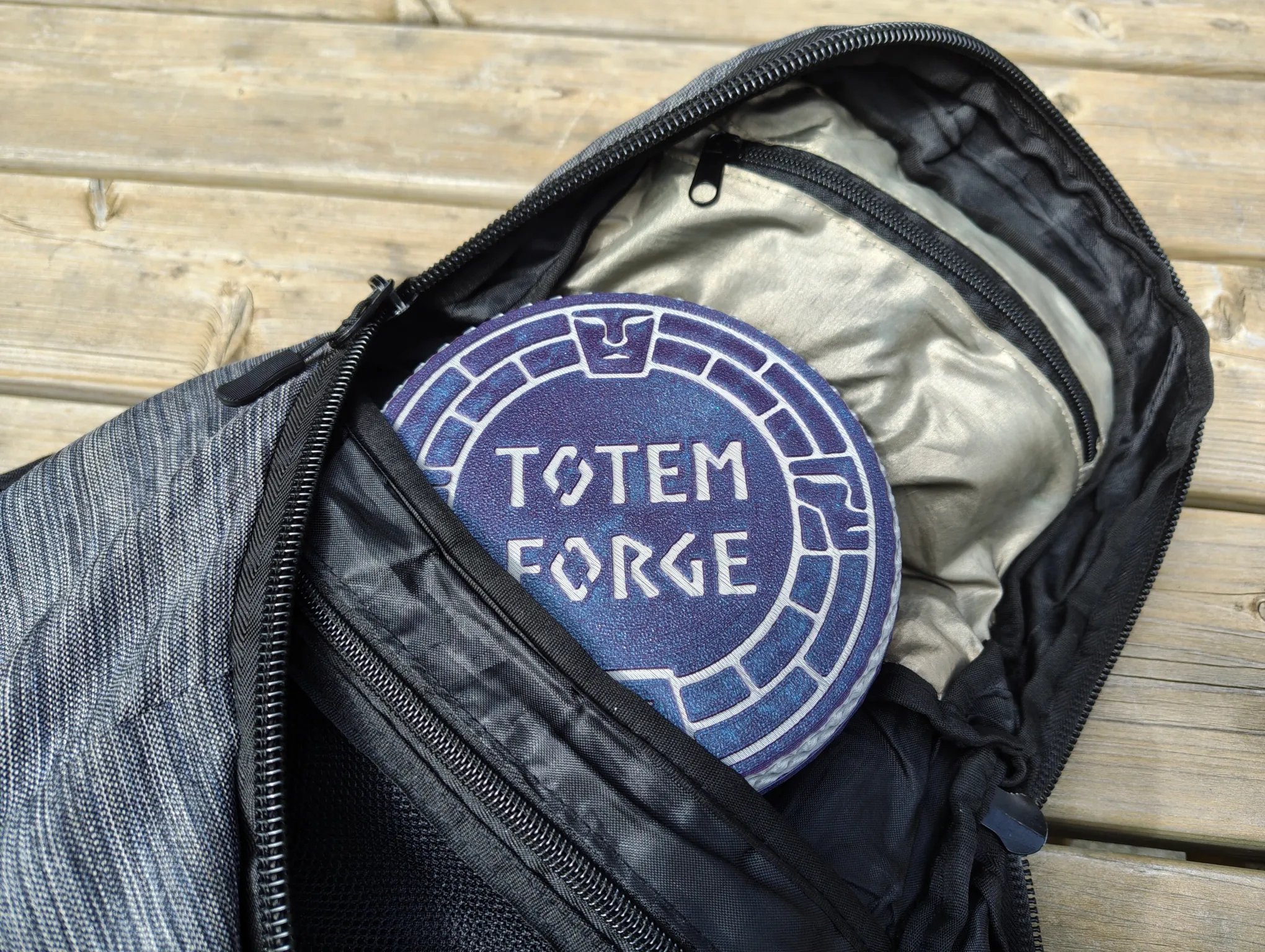 The round Totem Forge case tucked into a backpack pocket